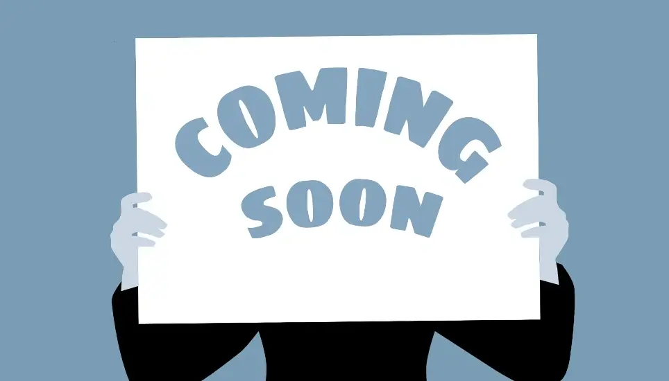 personne tenant un panneau COMING SOON